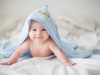 Cute little baby boy, relaxing in bed after bath, smiling happily, daytime